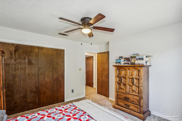 bedroom with light carpet, a textured ceiling, a closet, and ceiling fan