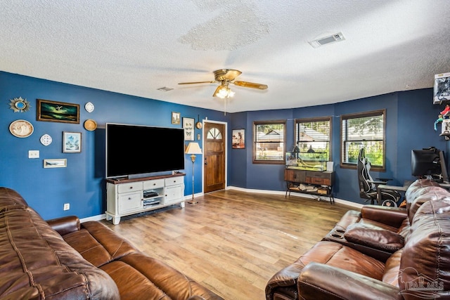 living room with ceiling fan, light wood-type flooring, and a textured ceiling