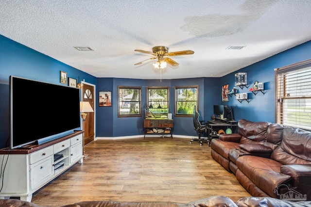 living room featuring a wealth of natural light, ceiling fan, a textured ceiling, and light wood-type flooring