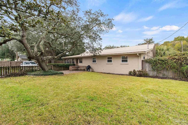 back of property featuring concrete block siding, metal roof, a yard, and fence