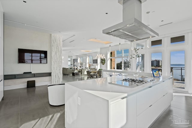 kitchen featuring white cabinetry, hanging light fixtures, dark tile patterned flooring, island exhaust hood, and a large island