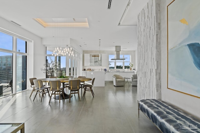 dining area with a notable chandelier, a raised ceiling, and a wealth of natural light