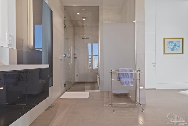 bathroom featuring toilet, an enclosed shower, and tile patterned flooring