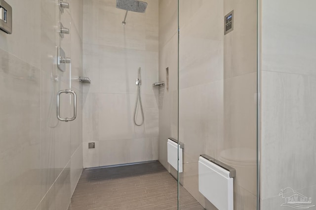 bathroom featuring a shower with door and radiator