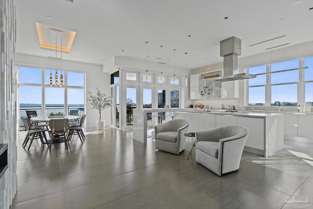 living room featuring an inviting chandelier, a towering ceiling, and a water view