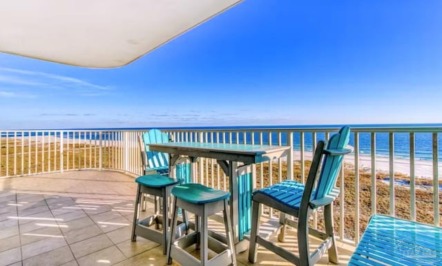 balcony with a water view and a view of the beach