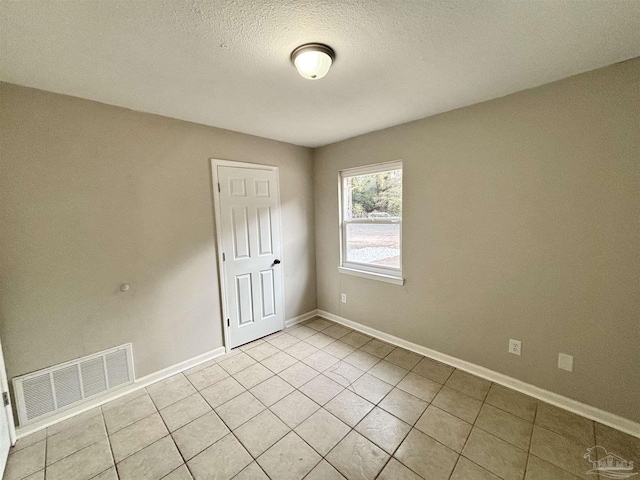 tiled empty room featuring a textured ceiling