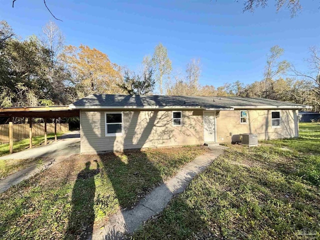 rear view of property with central air condition unit, fence, and a carport