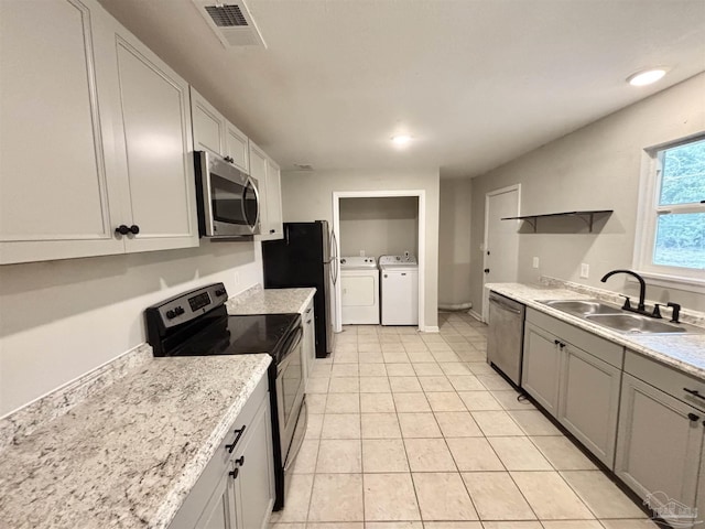 kitchen featuring stainless steel appliances, light tile patterned flooring, sink, and washer and clothes dryer