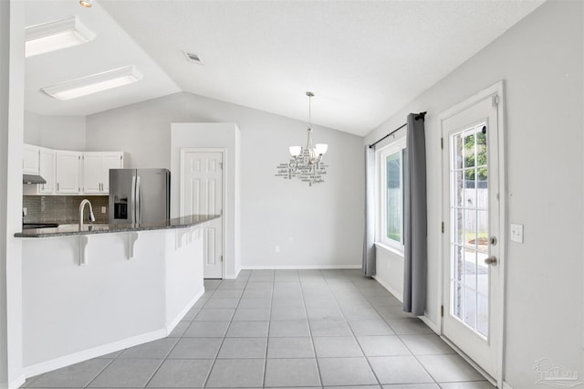 2252 Valle Escondido Dr, Pensacola, FL 32526 - kitchen with dark stone counters, visible vents, a kitchen bar, vaulted ceiling, and stainless steel refrigerator with ice dispenser