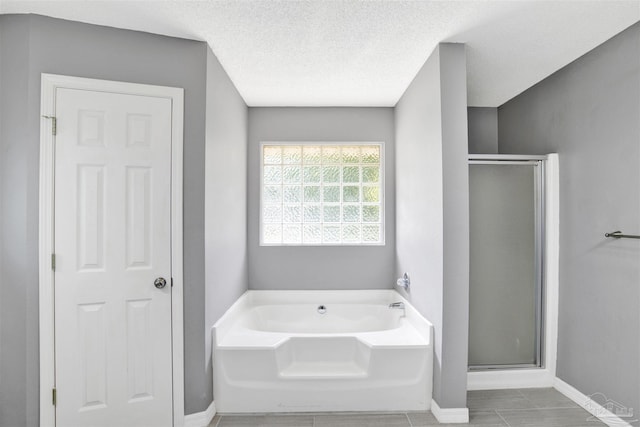 2252 Valle Escondido Dr, Pensacola, FL 32526 - bathroom featuring a textured ceiling, a garden tub, a shower stall, and baseboards