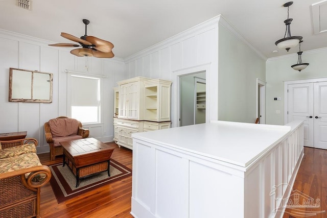 interior space featuring dark wood-style floors, visible vents, a kitchen island, open shelves, and ornamental molding