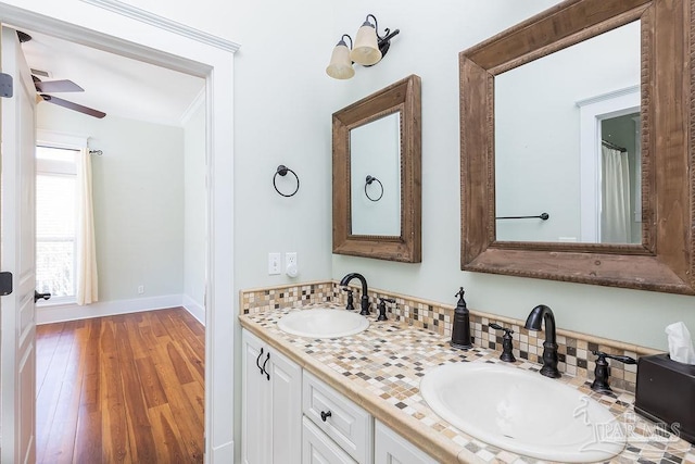 bathroom featuring double vanity, wood finished floors, baseboards, and a sink