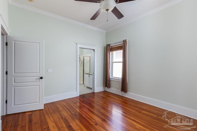 unfurnished bedroom featuring a ceiling fan, baseboards, hardwood / wood-style flooring, crown molding, and connected bathroom