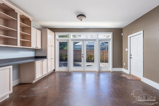 unfurnished dining area featuring finished concrete floors, french doors, and baseboards