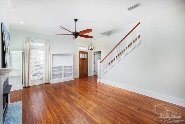 unfurnished living room featuring visible vents, stairway, wood-type flooring, crown molding, and baseboards