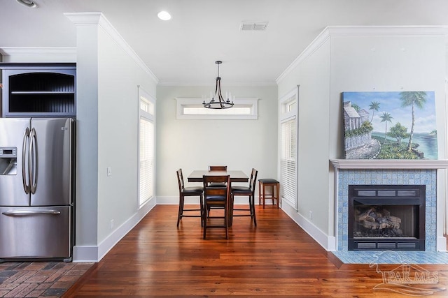 dining room with visible vents, baseboards, dark wood finished floors, ornamental molding, and a notable chandelier