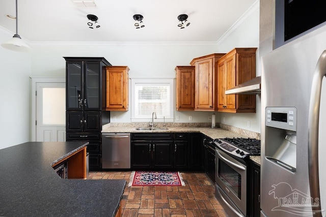 kitchen with ornamental molding, a sink, appliances with stainless steel finishes, exhaust hood, and brick floor