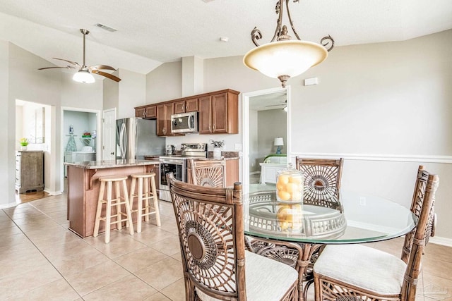 dining space with light tile patterned floors, vaulted ceiling, and ceiling fan