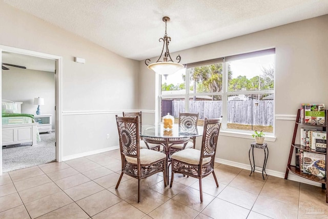 dining room with vaulted ceiling, a textured ceiling, and light tile patterned floors