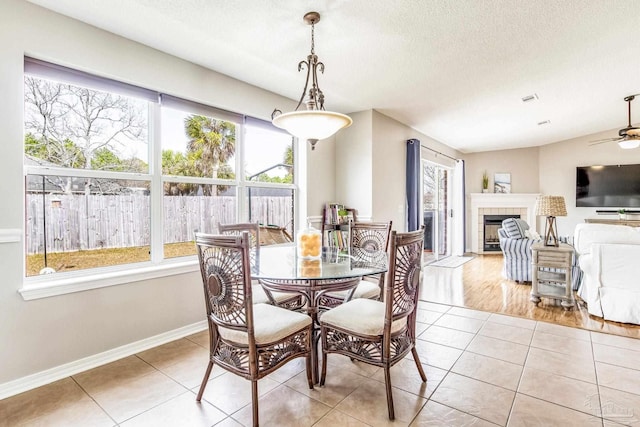 tiled dining space featuring a tiled fireplace, ceiling fan, and a textured ceiling