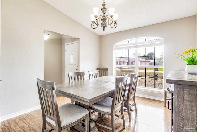 dining space with vaulted ceiling, an inviting chandelier, and light hardwood / wood-style floors