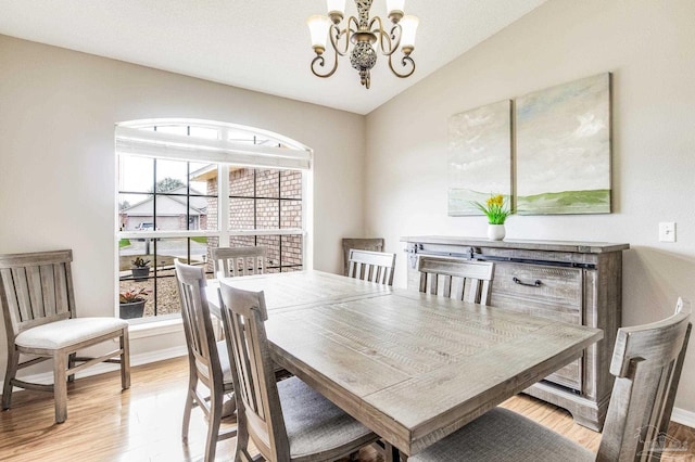 dining space featuring an inviting chandelier, lofted ceiling, and light hardwood / wood-style flooring