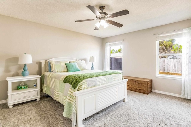 bedroom with multiple windows, light colored carpet, and a textured ceiling