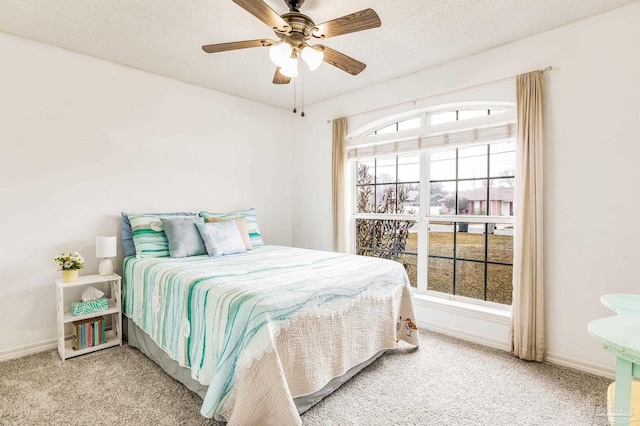 carpeted bedroom featuring ceiling fan and a textured ceiling