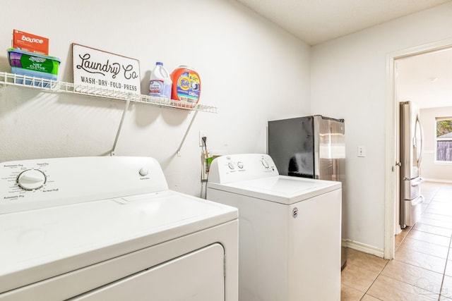 clothes washing area with light tile patterned floors and independent washer and dryer