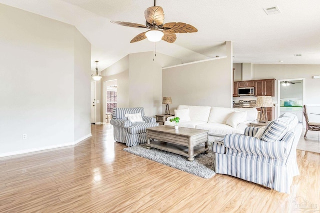 living room with lofted ceiling, a textured ceiling, light hardwood / wood-style floors, and ceiling fan