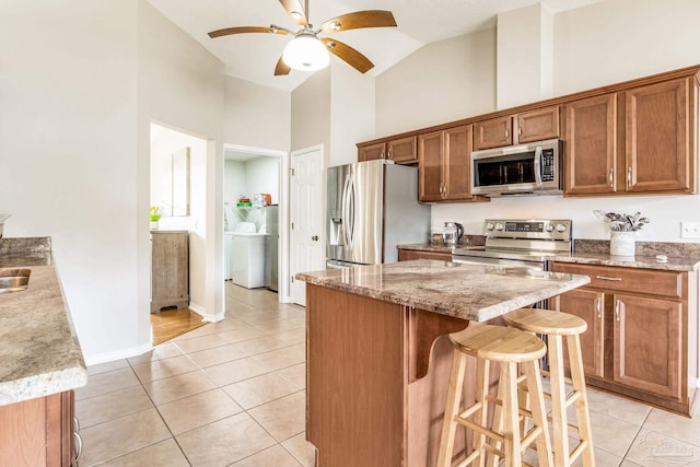 kitchen with light tile patterned floors, a breakfast bar area, high vaulted ceiling, and appliances with stainless steel finishes