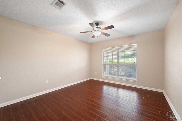 spare room featuring a textured ceiling and dark hardwood / wood-style flooring