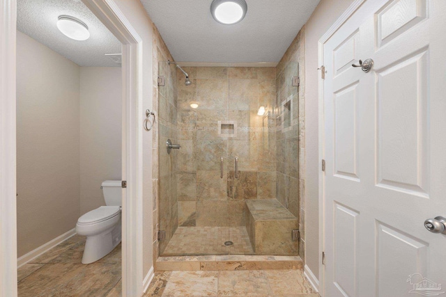 bathroom featuring a textured ceiling, toilet, and walk in shower