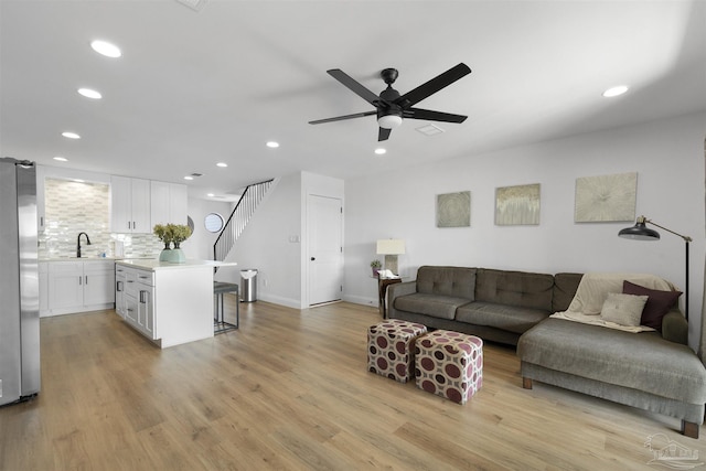 living room with ceiling fan, sink, and light wood-type flooring