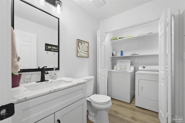 bathroom featuring vanity, wood-type flooring, toilet, and washing machine and clothes dryer