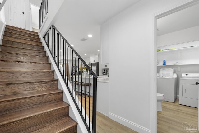 stairs with hardwood / wood-style floors and independent washer and dryer