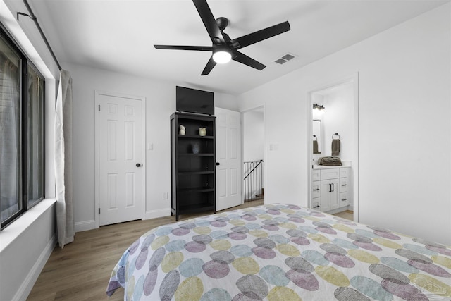 bedroom with ceiling fan, ensuite bath, and light wood-type flooring