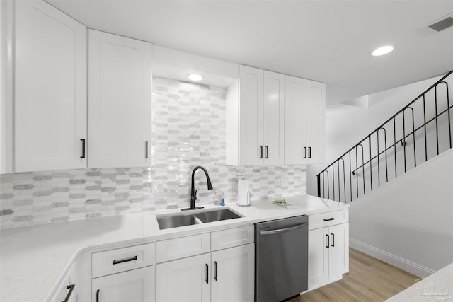 kitchen with sink, light wood-type flooring, dishwasher, white cabinets, and backsplash