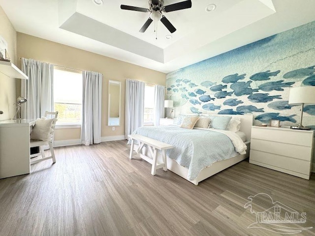 bedroom featuring a raised ceiling, ceiling fan, and hardwood / wood-style floors