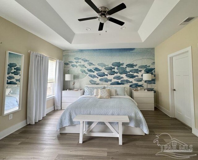 bedroom featuring a tray ceiling, ceiling fan, and wood-type flooring