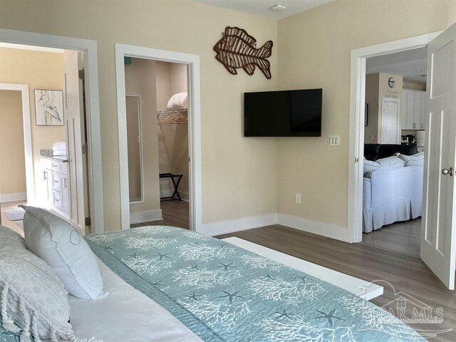 bedroom featuring a walk in closet, hardwood / wood-style flooring, and a closet