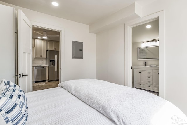 bedroom with hardwood / wood-style flooring, ensuite bathroom, electric panel, and stainless steel fridge with ice dispenser