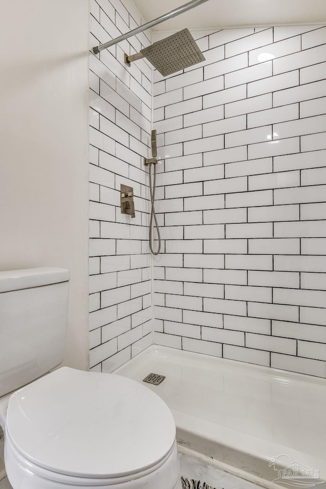 bathroom featuring tiled shower and toilet