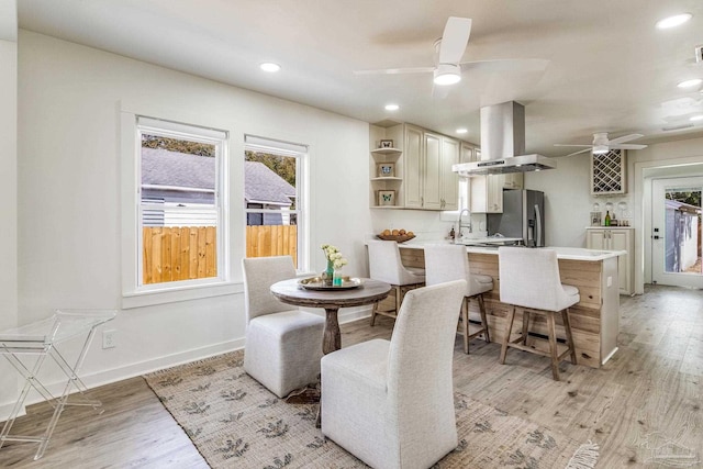 dining space featuring sink, light hardwood / wood-style flooring, and ceiling fan