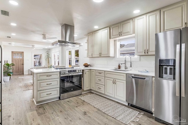 kitchen with sink, appliances with stainless steel finishes, island exhaust hood, kitchen peninsula, and light wood-type flooring