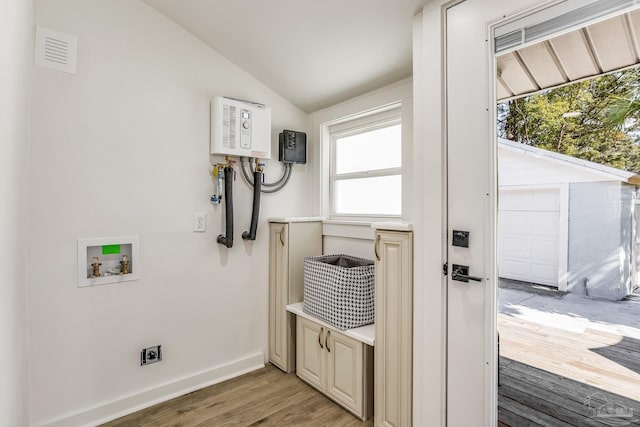 washroom with electric dryer hookup, washer hookup, hardwood / wood-style floors, and water heater