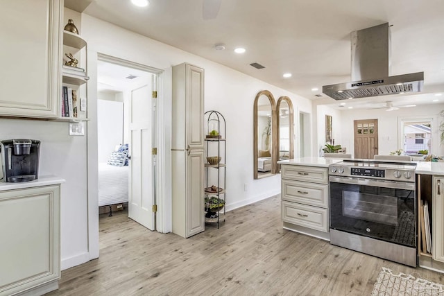 kitchen with island range hood, stainless steel electric stove, and light hardwood / wood-style floors