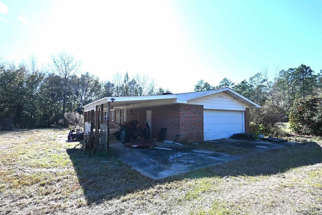 view of front of house with an attached garage, driveway, a front lawn, and brick siding