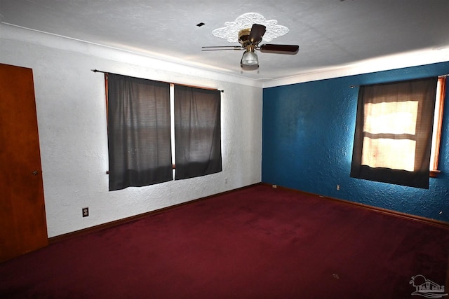 spare room featuring carpet floors, a textured wall, and a ceiling fan